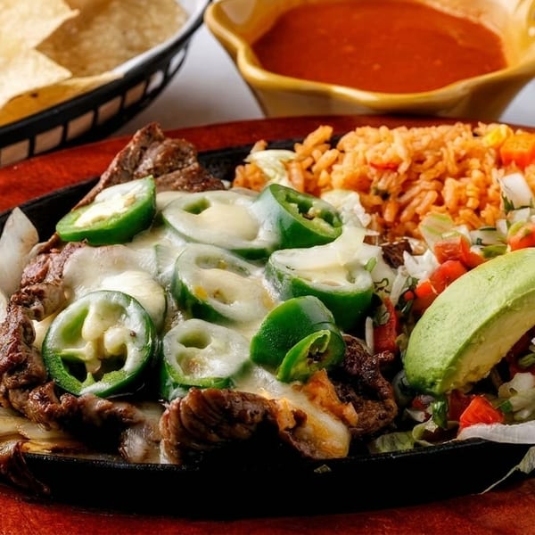 Sizzling fajitas with steak, melted cheese, jalapeños, onions, rice, avocado, and pico de gallo.